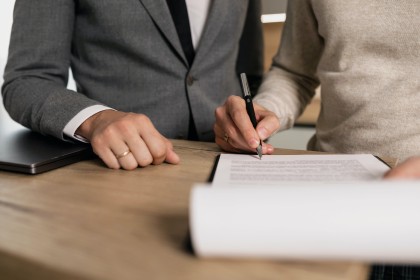 Two people reviewing and signing a document at a desk