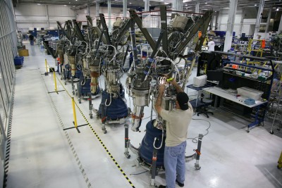 Technicians working among rocket engine assemblies in a manufacturing facility