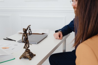 A person reviewing paperwork at a desk with a small Lady Justice statue